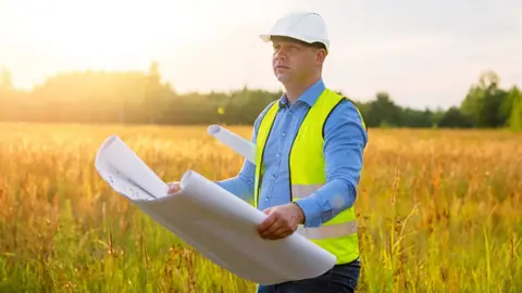 Architekt z planem budowy na działce budowlanej